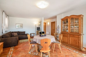 A living room with a sofa, chairs, a dining table, a cabinet, and a television. - Apartment 'Laurin' with Vineyard & Mountain Views (Kaltern)