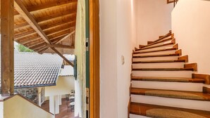 Una escalera de madera con una pared blanca y un techo de baldosas al fondo.