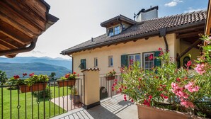 A house with a balcony, a view of mountains, and potted plants. - Studio 'Vitis' with Mountain View, Private Terrace and Wi-Fi (Kaltern)