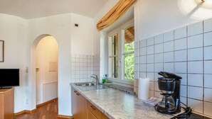 A kitchen with a granite countertop, a coffee maker, a sink, and a window with a view of greenery. - Studio 'Vitis' with Mountain View, Private Terrace and Wi-Fi (Kaltern)