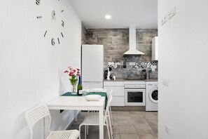 Une cuisine compacte avec un réfrigérateur blanc, un lave-linge et un coin repas comprenant une table et des chaises.