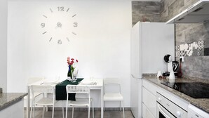 A modern kitchen with white cabinetry, a built-in oven, and a large wall clock. - Apartment "EleMe I" with Private Terrace & Wi-Fi (Vejer)