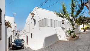 A narrow street with a car parked on the left, white buildings, and a tree on the right. - Apartment "EleMe I" with Private Terrace & Wi-Fi (Vejer)