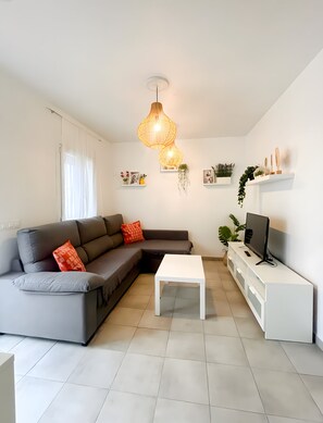 A modern living room with a sectional sofa, a white coffee table, a flat-screen TV on a white entertainment unit, and a hanging light fixture. - Apartment "EleMe I" with Private Terrace & Wi-Fi (Vejer)