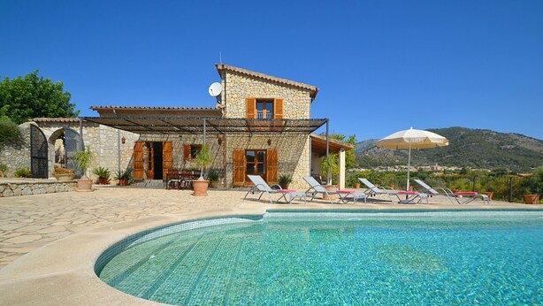 A stone villa with a swimming pool, lounge chairs, and a mountain backdrop. - Country House 'Sa Volta' with Mountain View, Wi-Fi and Air Conditioning (selva)