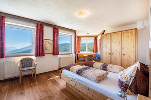 Une pièce comprenant un lit, une chaise, une table et donnant sur l’extérieur.