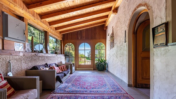 A wooden interior with a large rug, wicker furniture, and a view through arched windows. - Apartment 'Apt Gaisler' with Mountain View, Private Terrace and Wi-Fi (Maranza)