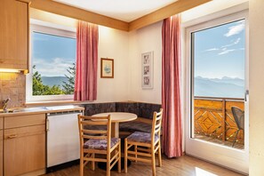 Cucina angolare con zona pranzo, lavastoviglie e vista sulle montagne attraverso una finestra.