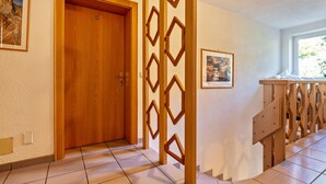 A hotel hallway with a wooden door, a decorative wooden partition, and a bed with a wooden headboard. - Studio Apartment 'Spinges' with Mountain View, Private Terrace and Wi-Fi (Maranza)