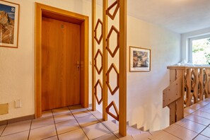 Un pasillo de hotel con una puerta de madera, un separador decorativo de madera y una cama con cabecera de madera.