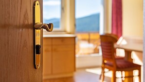 A wooden door with a brass handle, a window with a view of mountains, and a wooden chair in a room. - Cozy Waldblick Apartment with Mountain Views & Terrace in Meransen (Maranza)