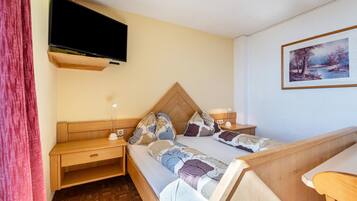 Une chambre à coucher avec un lit, un bureau, une télévision et un tableau accroché au mur.