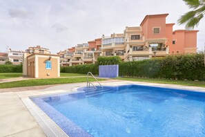 A swimming pool with a metal ladder, surrounded by a paved area, with multi-story residential buildings in the background. - 'Frontline Vacation Home A86' Apartment with Sea Views, Shared Pool and Wi-Fi (TORROX COSTA)