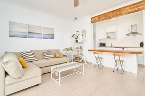 A modern living room with a sofa, a coffee table, and a kitchen area with a counter and chairs. - 'Frontline Vacation Home A86' Apartment with Sea Views, Shared Pool and Wi-Fi (TORROX COSTA)