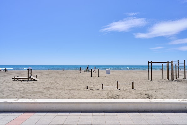 A beach with a clear sky, a sandy shore, and a wooden structure.
