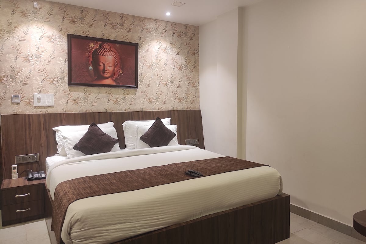 A neatly arranged hotel room with a large bed, a bedside table with a phone, and a wall-mounted picture.