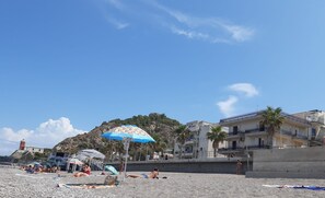 A beach with umbrellas, a lighthouse, and buildings in the background. - Holiday Apartment 'Solkira' close to the Beach with Sea View, Balcony & Wi-Fi (Capo d'Orlando)