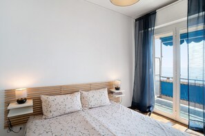 Un dormitorio con cama, lámparas de noche, mesita de noche y vistas a través de un ventanal.