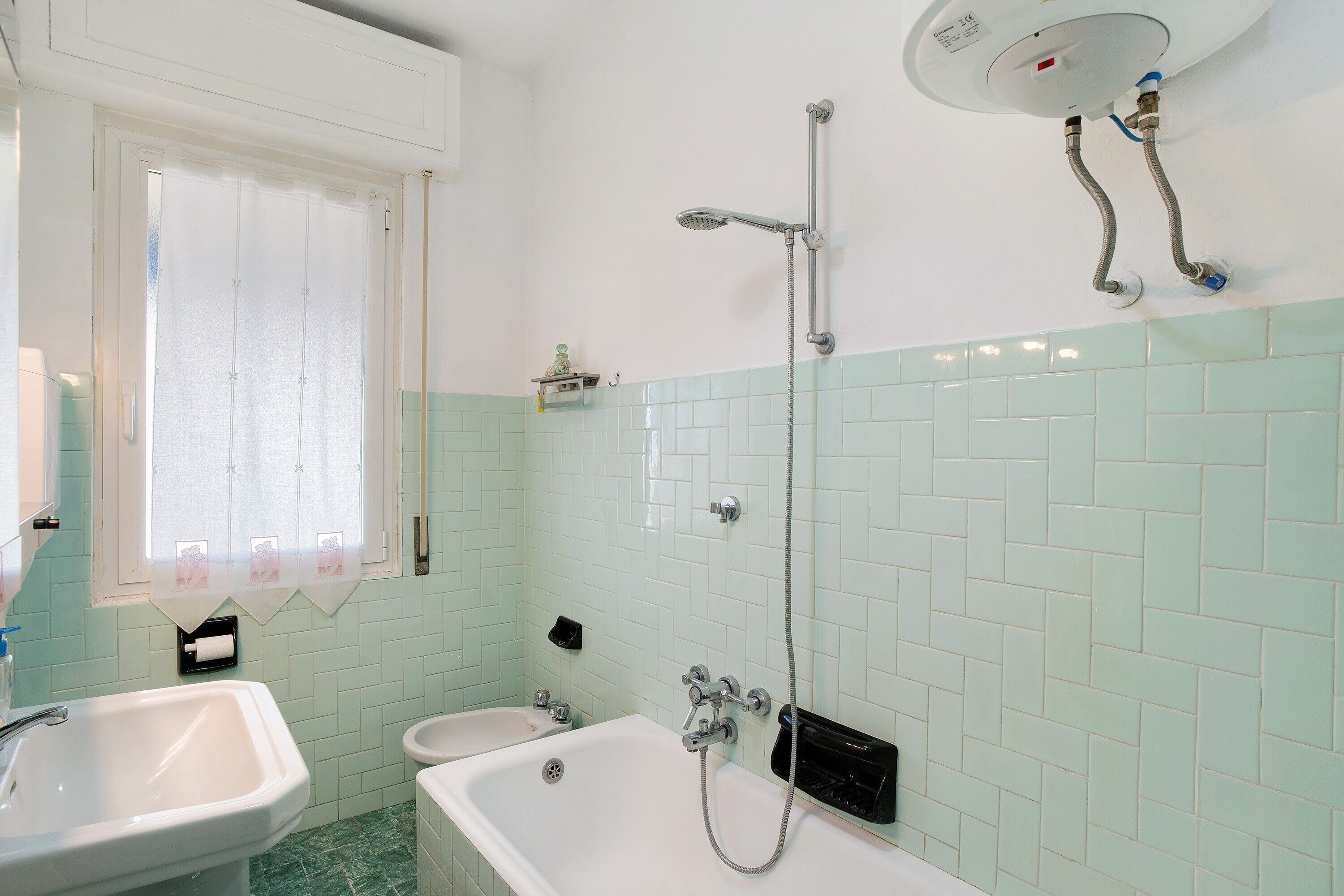 Ein Badezimmer mit Badewanne, Waschbecken, Duschkopf und Toilette.