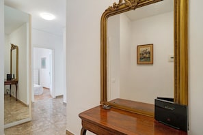 Una habitación con un espejo grande, un aparador de madera y un cuadro en la pared.