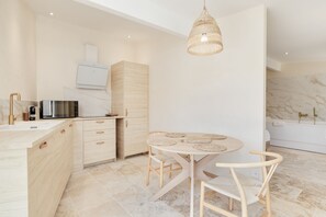 Una cocina moderna con comedor, que incluye una mesa redonda con sillas, una lámpara colgante y un horno empotrado.
