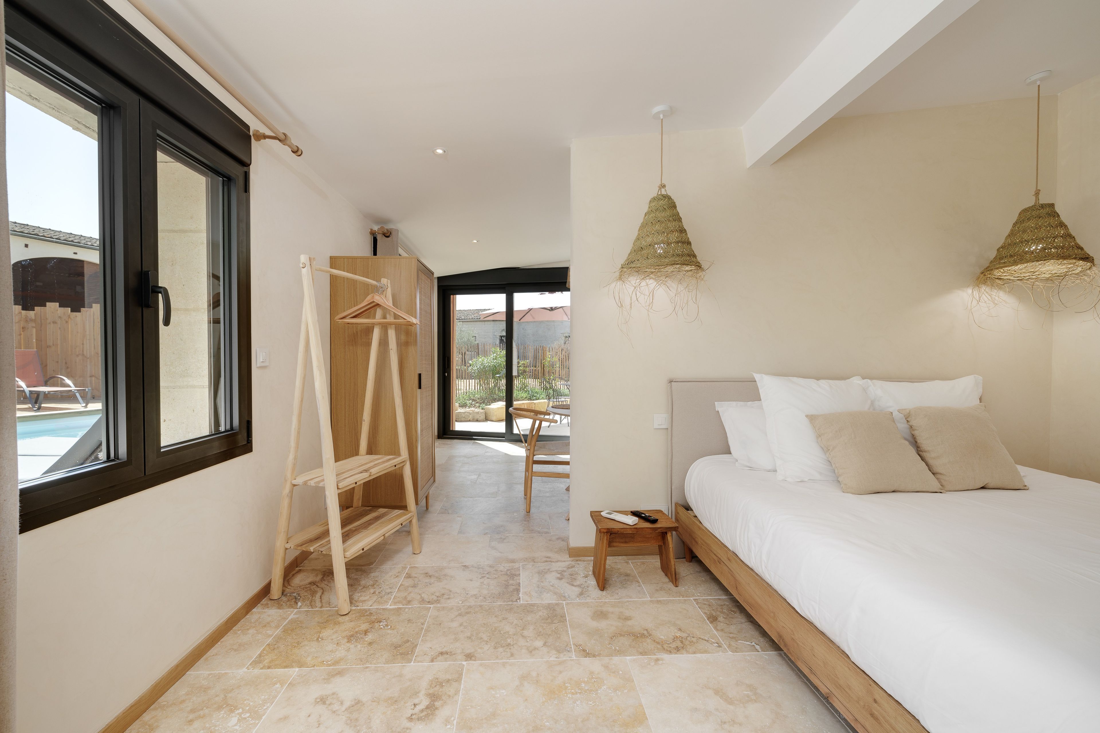 Un dormitorio con cama, mesita de noche y lámpara colgante.