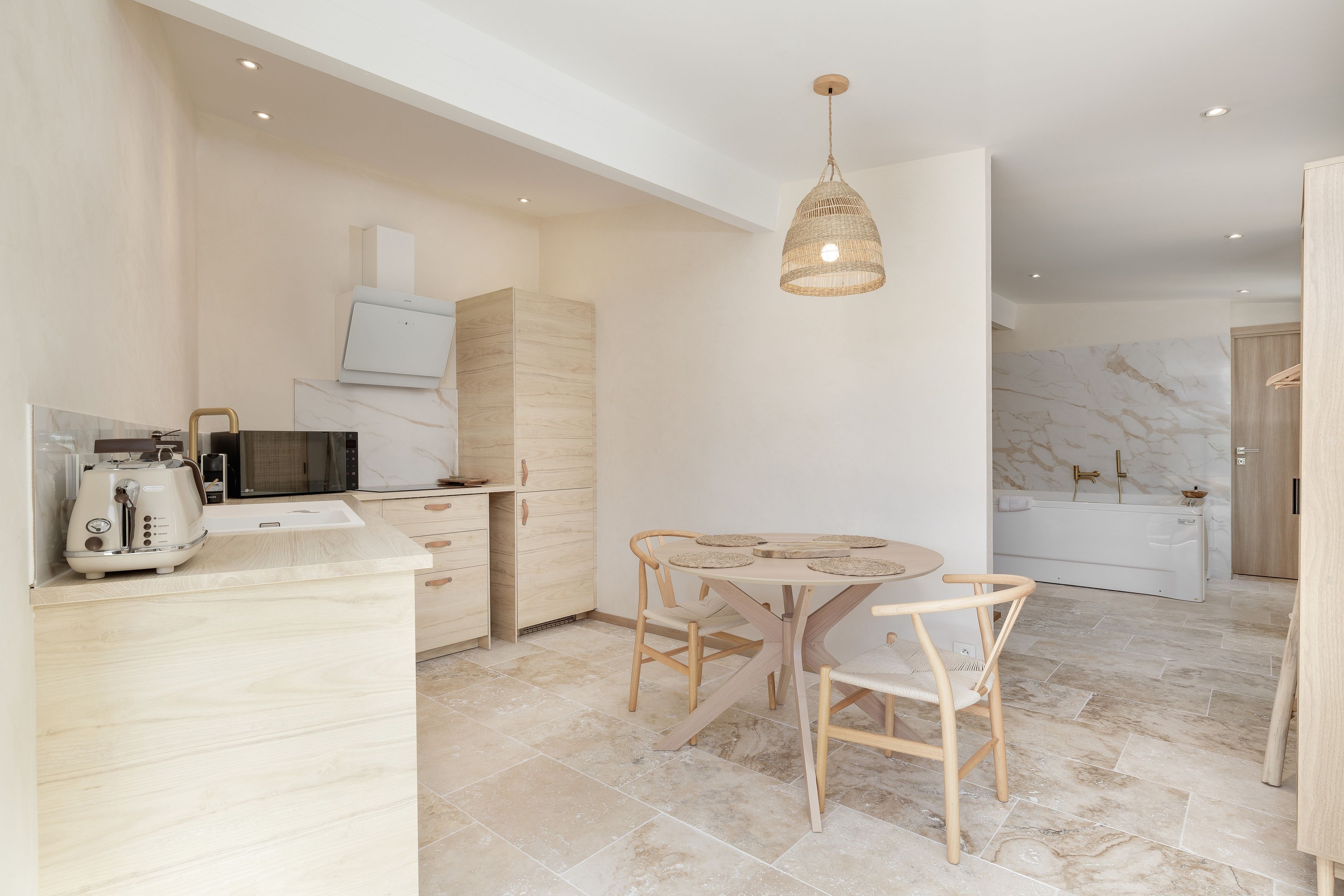 Een moderne keuken met een eetgedeelte, met een ronde tafel, stoelen en een hanglamp.