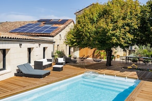Un espace piscine aménagé sur le toit, doté de panneaux solaires, de mobilier d’extérieur et d’un arbre.