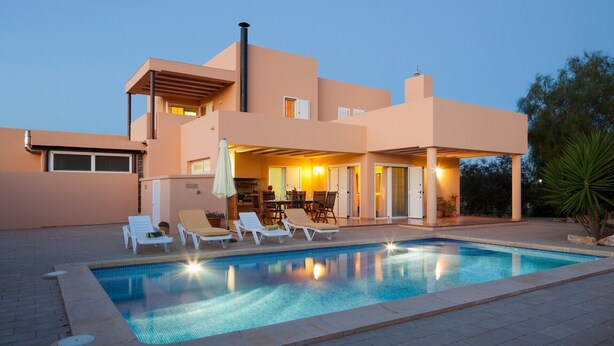 Une maison moderne dotée d’une piscine, de chaises longues et d’un patio couvert.