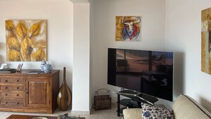 Un salon doté d’un téléviseur à écran plat, d’un meuble en bois, d’un vase décoratif et d’œuvres d’art accrochées aux murs.