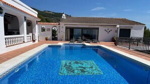 Une piscine avec une terrasse carrelée, un patio couvert et une vue sur les montagnes.