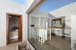 Une cuisine moderne avec un plan de travail en bois, des tabourets blancs et un lave-linge.
