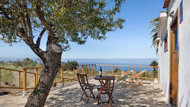 A patio with a table and chairs, overlooking a scenic view. - Vacation Home "Centenary Canarian Country House" with Sea View, Private Terrace & Wi-Fi (Punta Gorda)