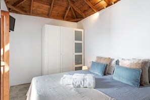 Une chambre à coucher avec un lit, des oreillers, une armoire et un téléviseur.