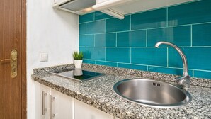 Una cocina con encimera de granito, pileta de acero inoxidable y salpicadero color turquesa.