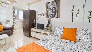 Un dormitorio moderno con una cama, un televisor, una estatua y una pintura de Buda.