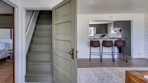 Une cuisine moderne dotée d’un îlot central, de tabourets de bar et d’un escalier menant à une chambre.