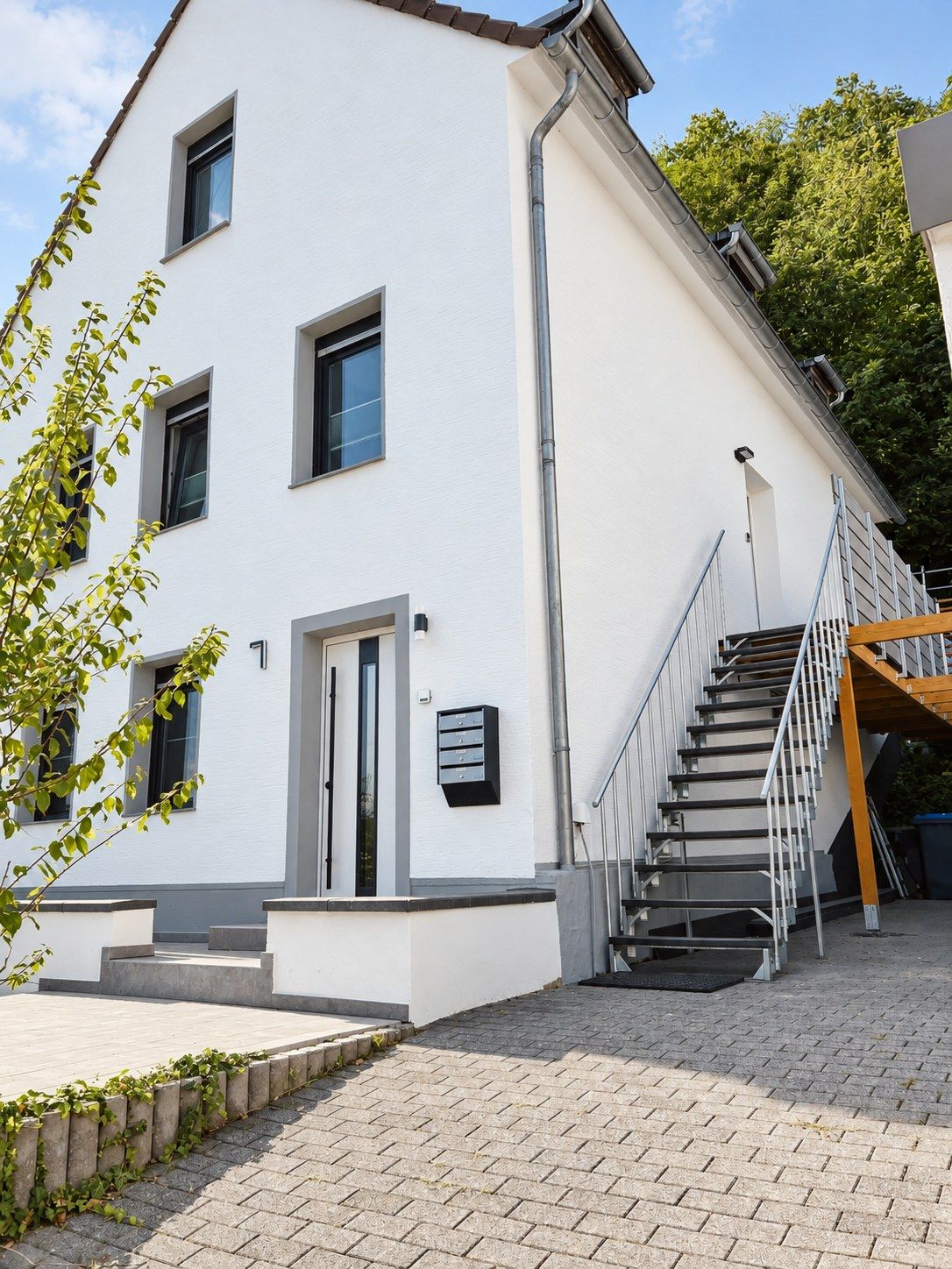 Un edificio blanco con una escalera que lleva a una terraza de madera.