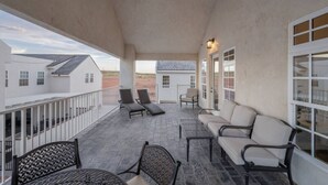 Un patio techado al aire libre con sillones y una mesa, con vista a una zona residencial.