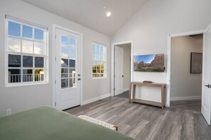 A spacious room with a large bed, a wooden console table, and a painting of a mountain landscape.