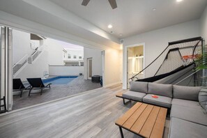 A modern living room with a grey sofa, a wooden coffee table, and a basketball hoop.