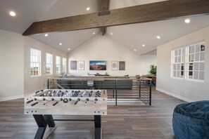 A spacious room with a foosball table, a dining area, and a large window with a view.