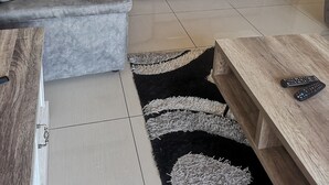 Un salon moderne avec deux canapés gris, une table basse en bois et un tapis noir.