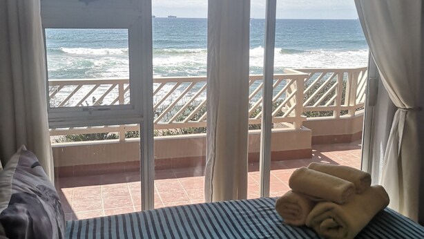 Une chambre avec un lit, une vue sur l’océan et un balcon doté d’une balustrade.