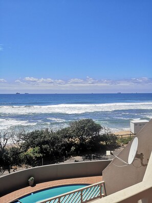 A balcony with a view of the ocean, a pool, and a satellite dish. - 15 Isikhulu (eMdloti)