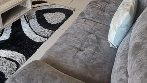 Un salon avec un canapé gris, une table basse en bois et un tapis noir et blanc.
