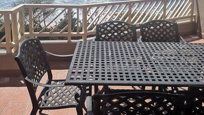 Un balcon avec une table et des chaises donnant sur l’océan.