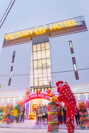 Un hôtel avec une grande enseigne lumineuse sur laquelle on peut lire « VICTORY HOTEL ».