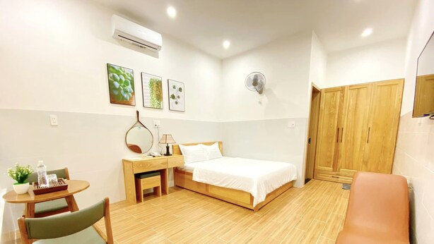 Une chambre d’hôtel comprenant un lit, un bureau avec une chaise, une petite table avec une plante et une armoire.