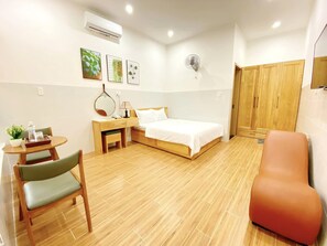 Une chambre d’hôtel comprenant un lit, un bureau avec une chaise, une petite table avec une plante et une armoire.